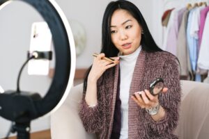 vlogger applying makeup and live streaming with her phone